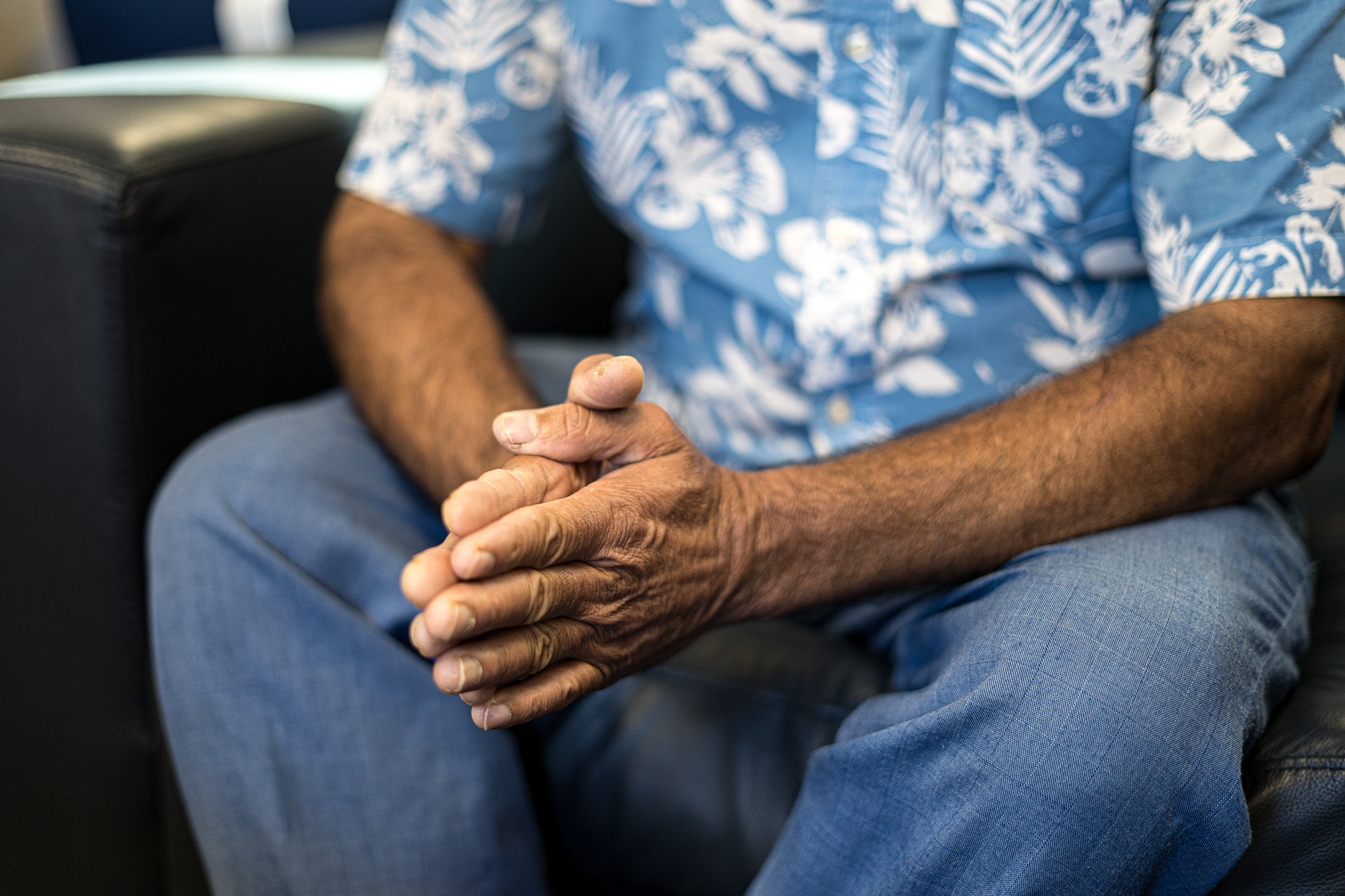 Man sitting with hands clasped at a neighbourhood food bank.