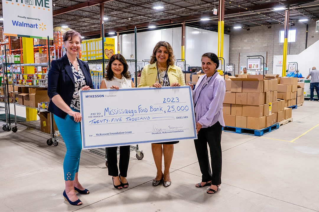 4 people smiling in warehouse holding large novelty check