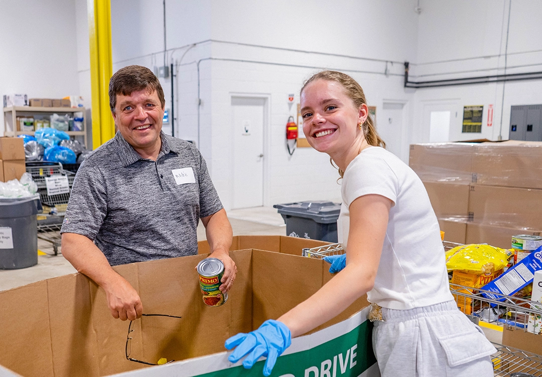 Warehouse volunteers smiling and facing the camera while sorting food