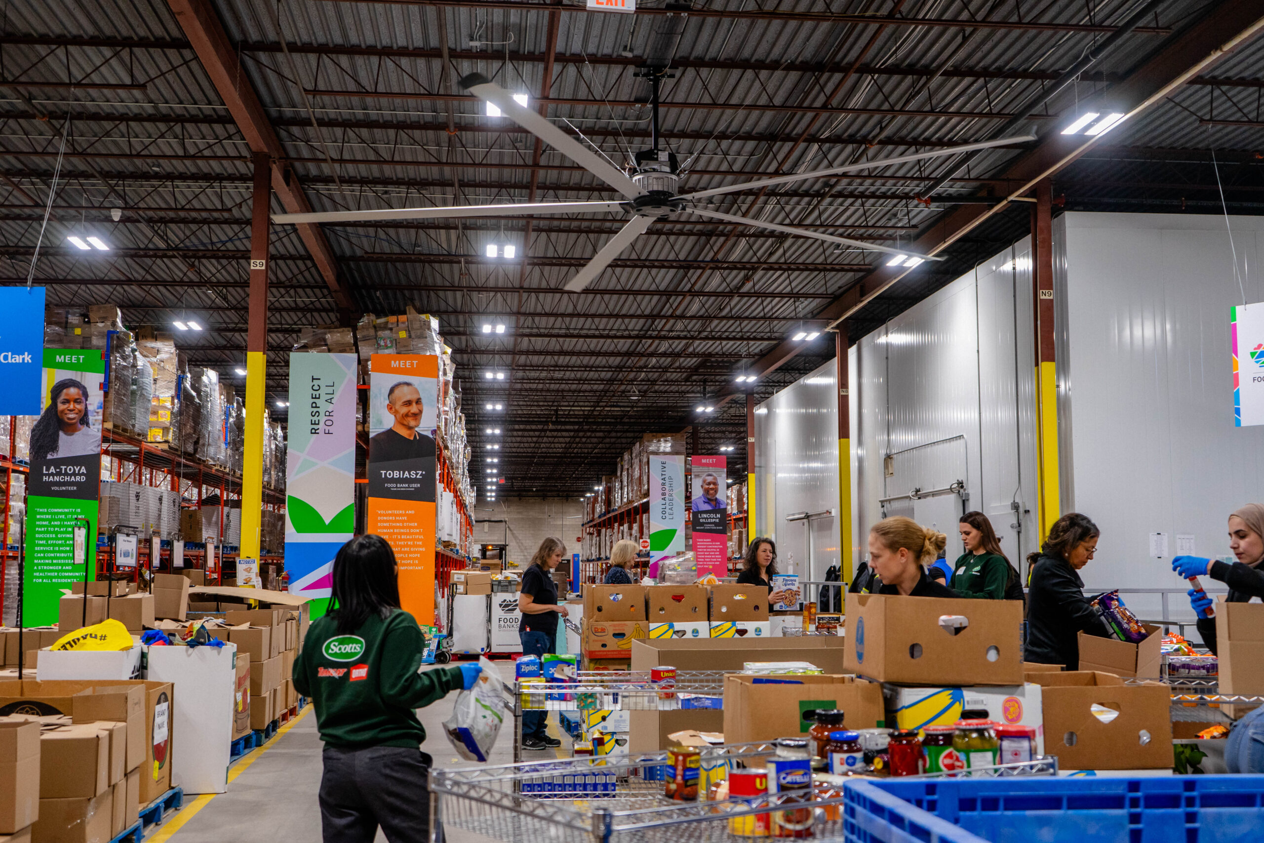A group of volunteers in the Food Banks Mississauga warehouse food sorting section.