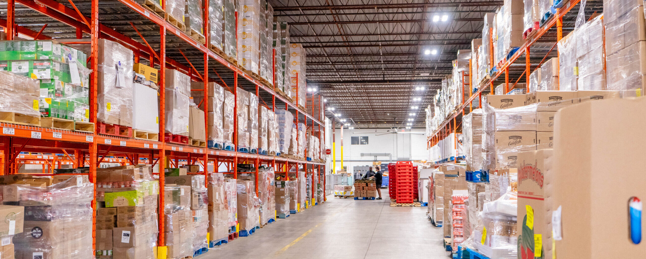 Food Banks Mississauga warehouse in between two aisles piled high with pallets of food.